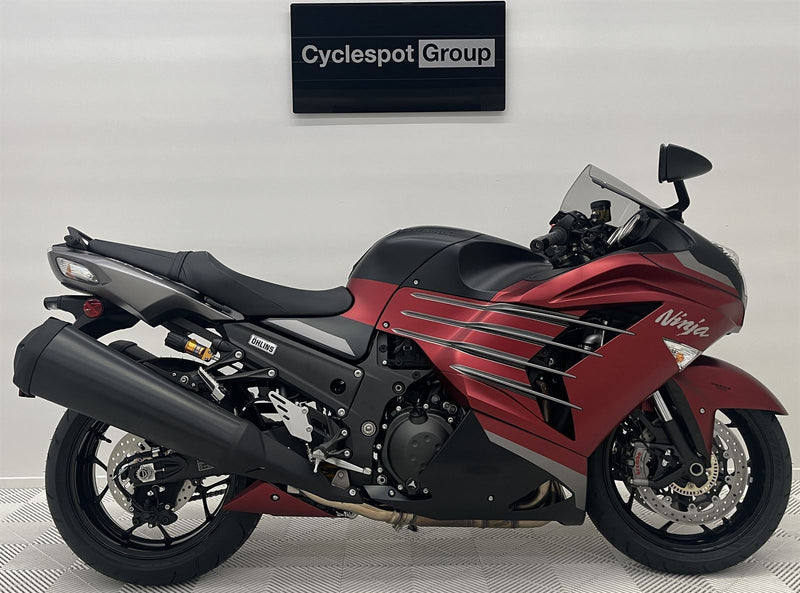 Load image into Gallery viewer, Red and black 2025 Kawasaki Ninja ZX 14 R SE motorcycle on display with 'Cyclespot Group' sign in the background