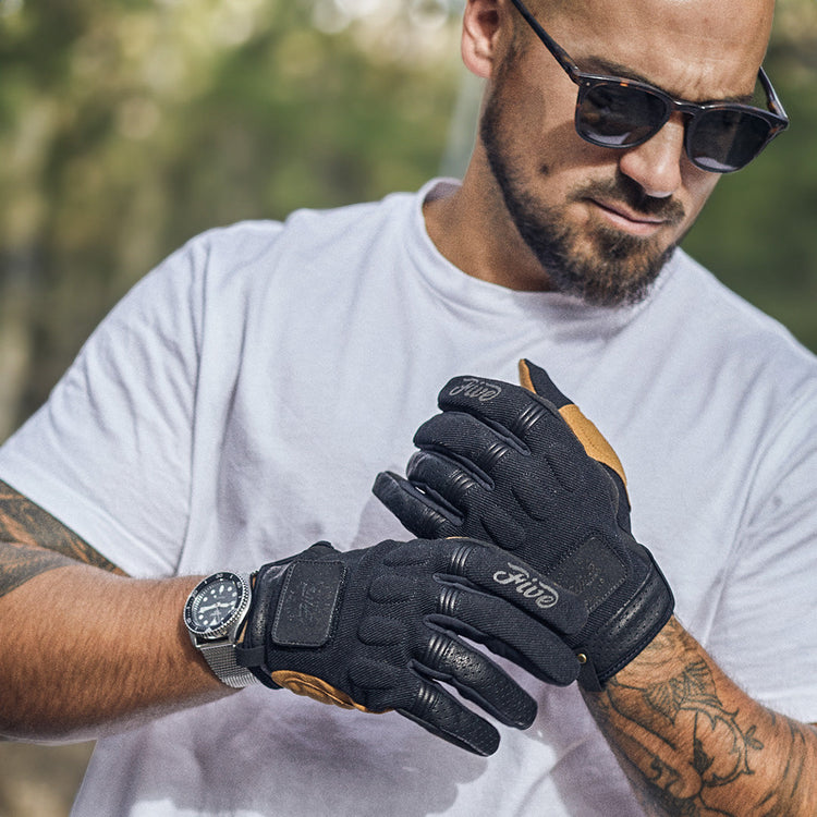 A rider wearing Five brand urban motorcycle gloves with tan leather accents and protective knuckle sliders. Premium men's riding gear available at Cyclespot Auckland, Taranaki, and Wellington.