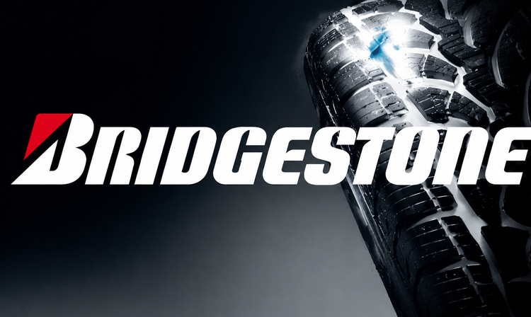 Bridgestone motorcycle tyre with illuminated tread and white Bridgestone logo on a dark background.