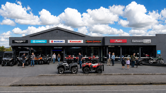 Cyclespot Taranaki motorcycle and ATV dealership exterior, displaying Triumph, CFMOTO, Suzuki, Kawasaki, Royal Enfield and Indian Motorcycle signage, with customers viewing vehicles outside.
