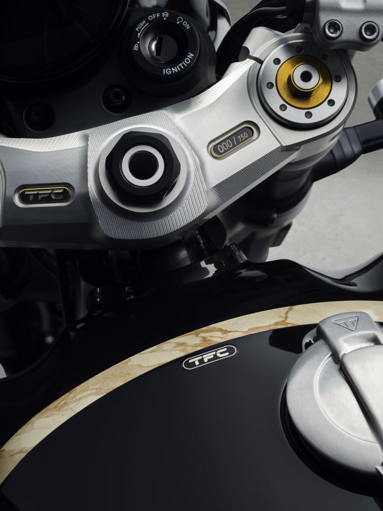 Load image into Gallery viewer, Close-up detail of a 2027 Triumph Speed Twin 1200 TFC motorcycle's handlebar area and fuel tank, showing silver and black components with gold and white TFC branding.
