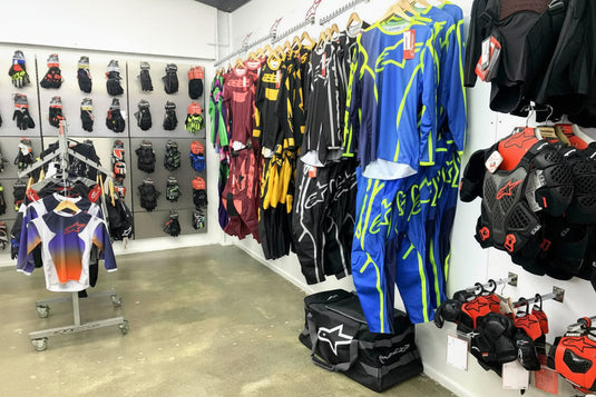 Showroom display at Cyclespot Taranaki featuring Alpinestars motocross jerseys, riding trousers