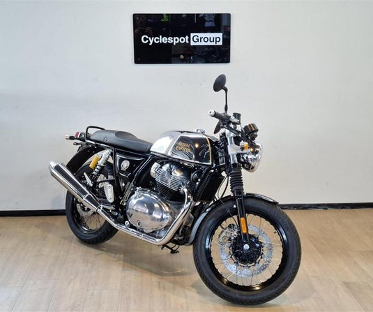 A 2026 Royal Enfield Continental GT Classic Cruiser motorcycle with a black and silver color scheme, parked indoors on a light wood floor against a white wall with a 'Cyclespot Group' sign above it.