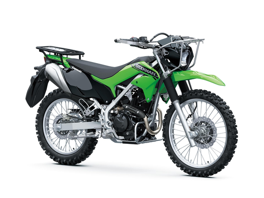 A green and black Kawasaki dirt bike with silver metal components, knobby off-road tires, and a rear luggage rack, photographed on a seamless white background.