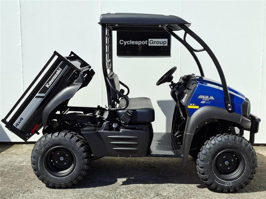 A 2017 Kawasaki Mule KAF 400 KH utility vehicle with a black roll cage and a raised black dump bed, parked against a white wall. The vehicle features a blue front hood and a black seat, with a 'Cyclespot Group' sign hanging behind it.